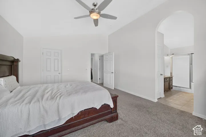 Vaulted ceiling, ceiling fan, arched doorway, panel doors, tiled bathroom flooring