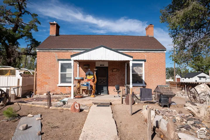 Brick exterior with two prominent chimneys, covered front porch, and a concrete pathway leading to the entrance