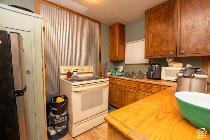 Kitchen featuring wood cabinetry, wood-finish countertops, corrugated metal accent wall, and a built-in stainless steel sink