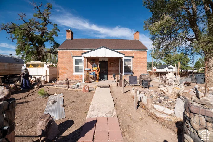 Red brick exterior with white trim windows, covered front porch, and a brown shingle roof