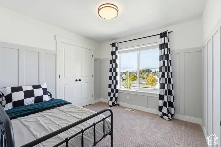 Board and batten wall detailing, large window with natural light, flush-mount ceiling light fixture, and carpeted flooring