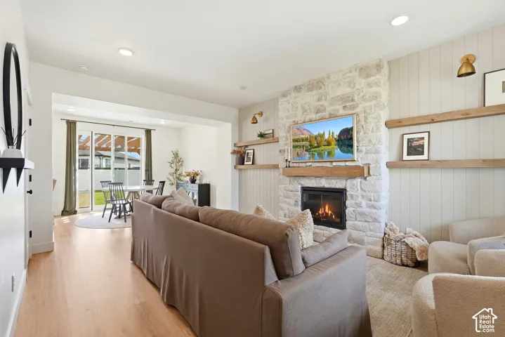 Stone-clad fireplace with wood mantel, built-in shelving, wood-finish flooring, and recessed lighting