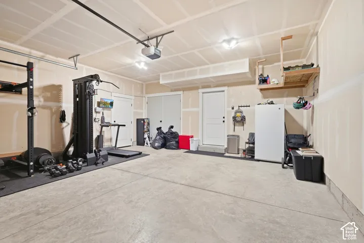 Concrete flooring with a built-in overhead storage shelf, recessed lighting, and an access door