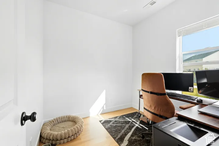 Light wood-finish flooring, white walls, and a large window providing ambient light