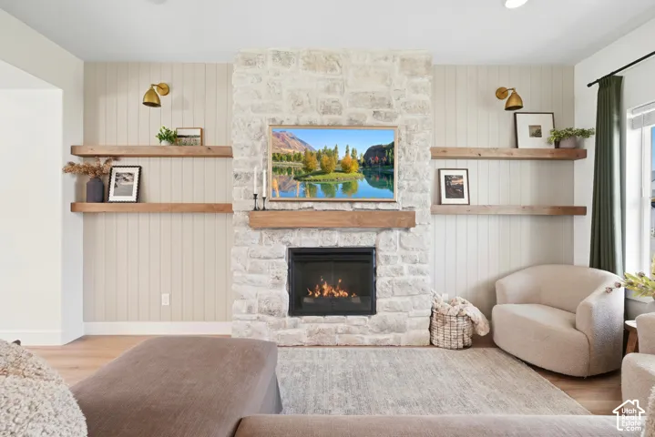 Stone-clad fireplace with a wood mantel, integrated television, and built-in shelving