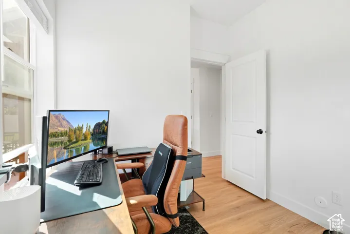 Light wood-finish flooring, white walls, white trim, and a white two-panel door