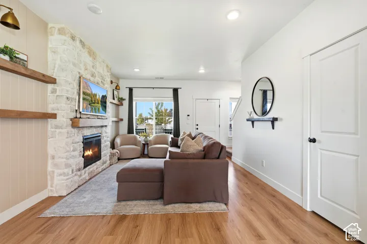 Stone-faced fireplace with a wood mantle, wood-finish flooring, and recessed ceiling lighting