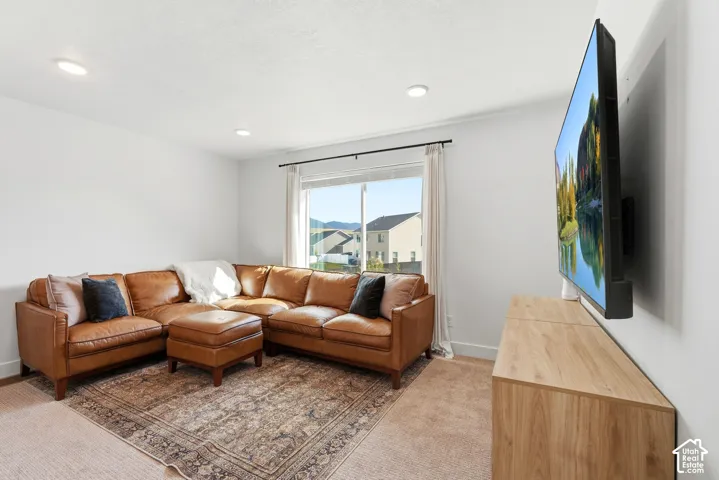 Recessed lighting, large window with outdoor scenery, light-colored walls, and wood-finish media console