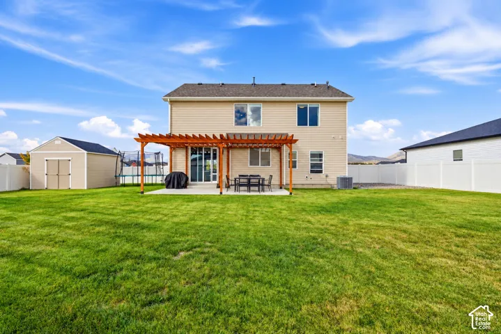 Expansive green lawn, concrete patio, wood pergola, and vinyl privacy fencing