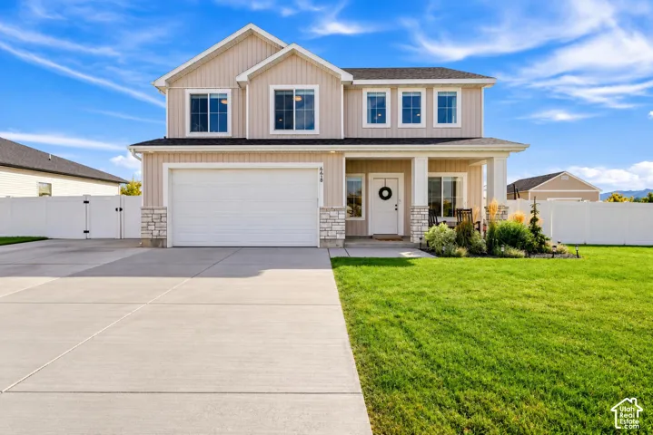 Two-story residence featuring light-toned siding, a two-car garage, and a covered front porch with white columns