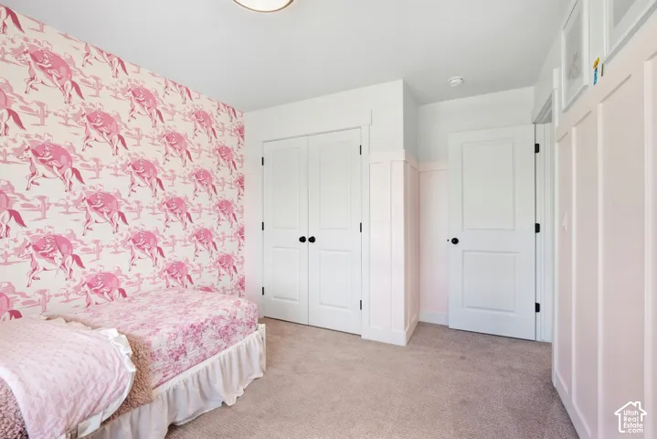 Wall-to-wall carpeting, white bi-fold closet doors, and panel molding