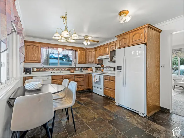 Kitchen featuring wood cabinetry, white appliances, a ceiling fan, and slate tile flooring