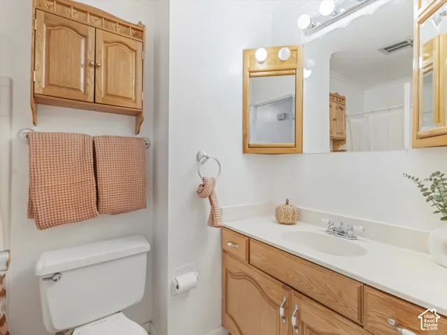 Vanity with integrated sink and chrome faucet, oak wood-finish cabinetry, and overhead lighting
