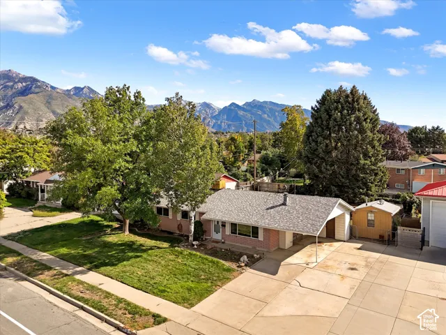 Mountain backdrop with a single-story residence, featuring a covered carport and a spacious paved driveway
