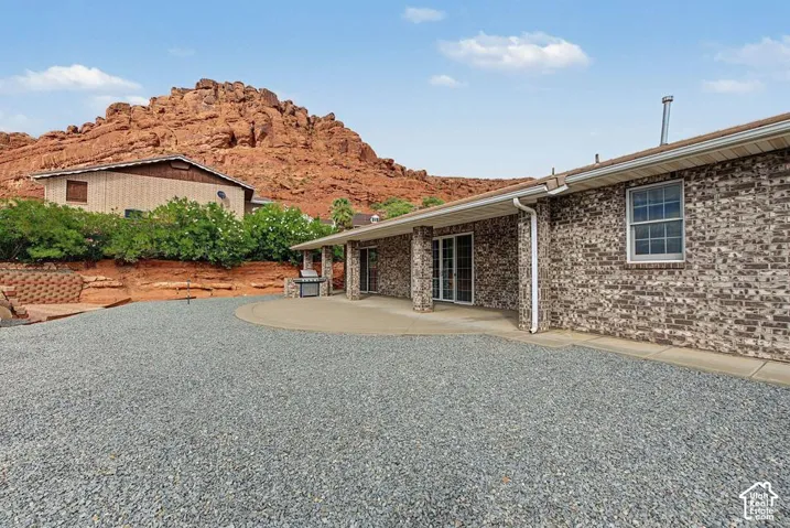 Brown brick exterior with a covered patio, sliding glass doors, and a gravel yard area