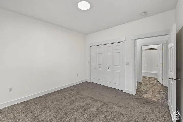 White walls with white trim, gray carpet flooring, and a flush mount ceiling light