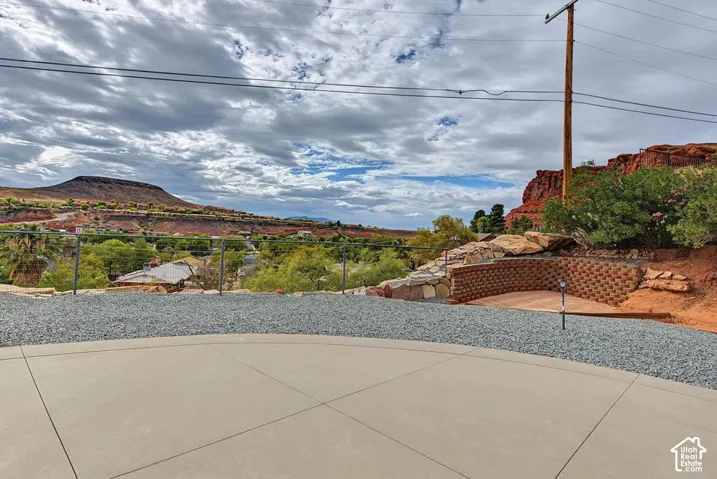 Concrete patio with gravel surround, retaining wall, and mountain backdrop