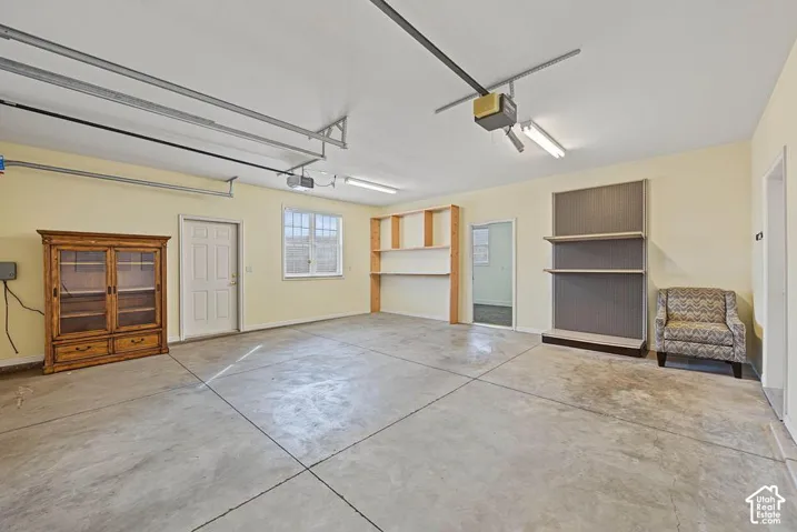 Concrete flooring, overhead lighting, built-in shelving, white paneled door, and a multi-pane window