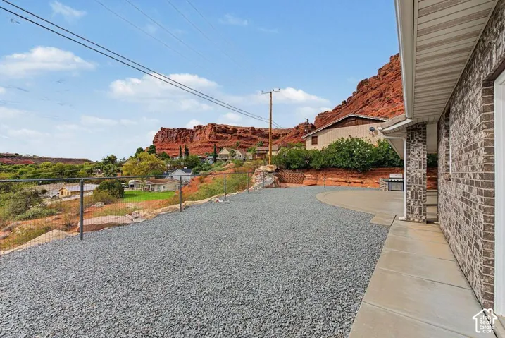 Gravel driveway with concrete walkway, brick exterior, and fence