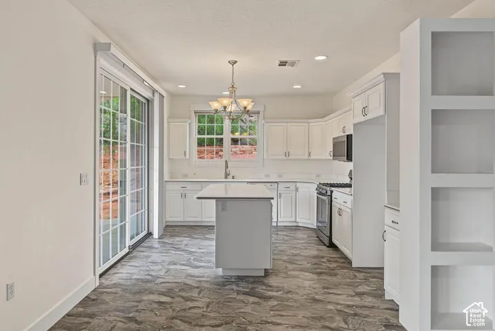 Kitchen featuring white cabinetry, a center island, stainless steel appliances, and stone-look tile flooring