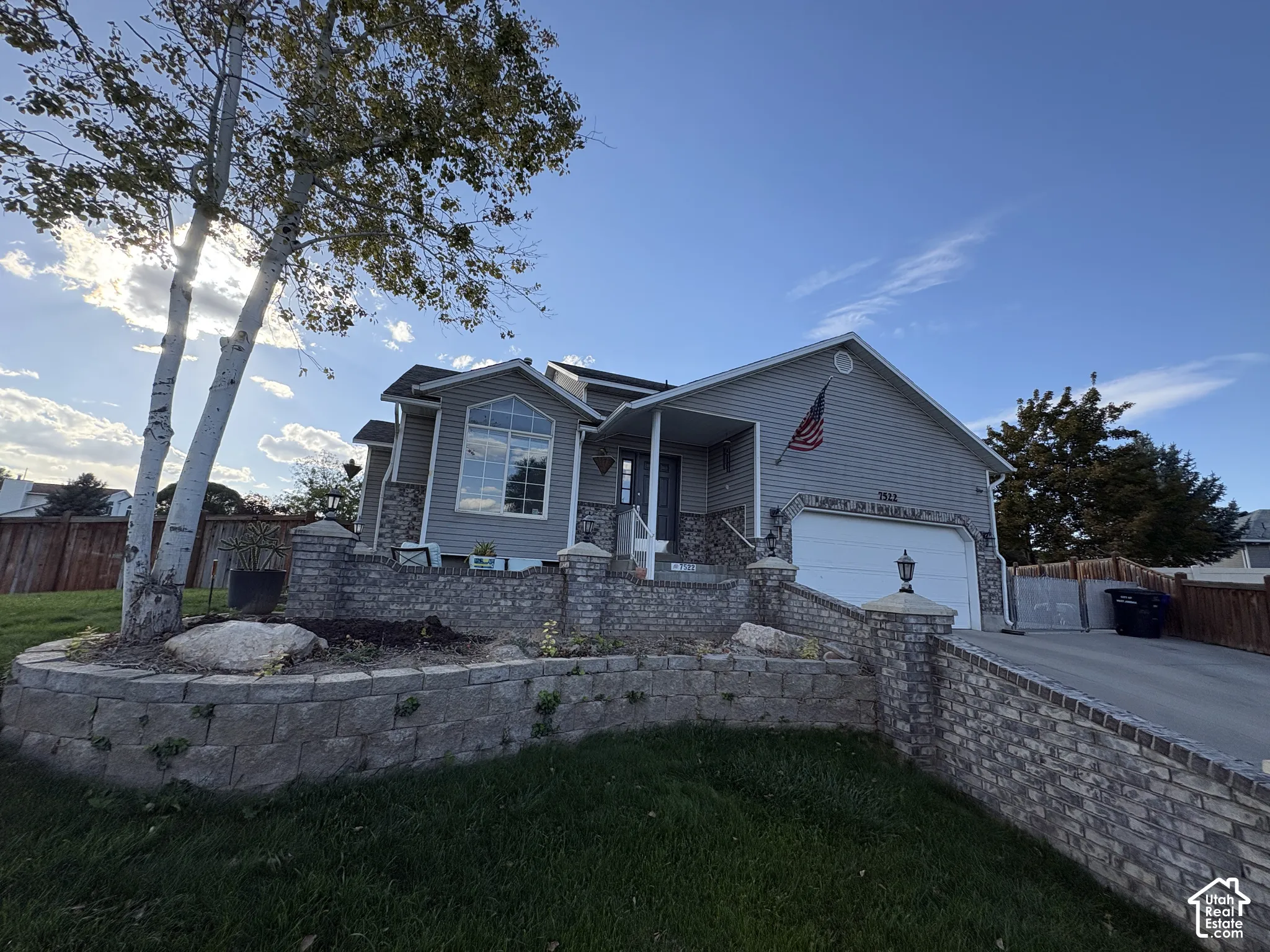 Exterior featuring siding and stone accents, an attached garage, a front porch