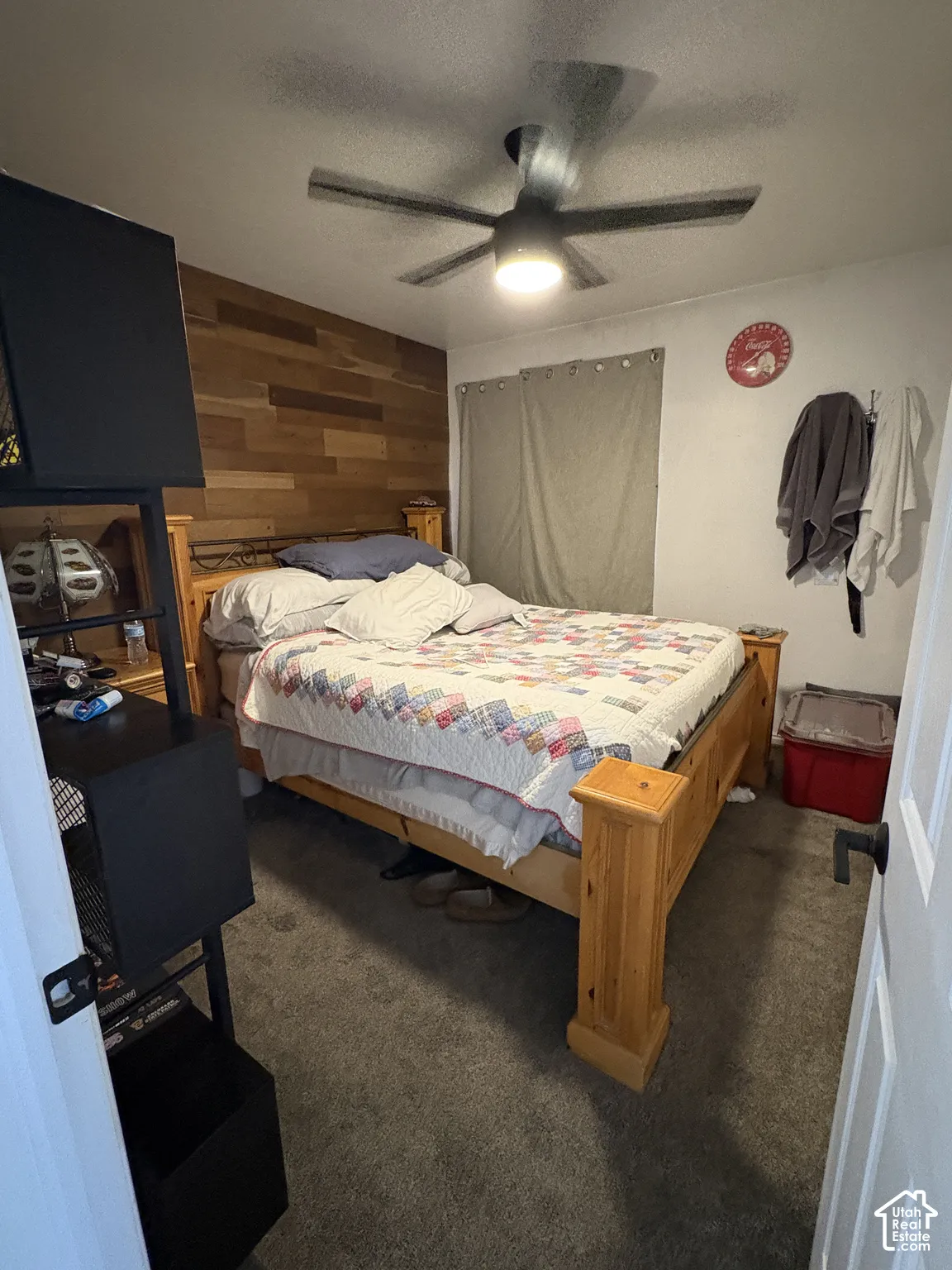 Secondary bedroom. Wood-finish accent wall, ceiling fan with integrated lighting, and neutral carpeting