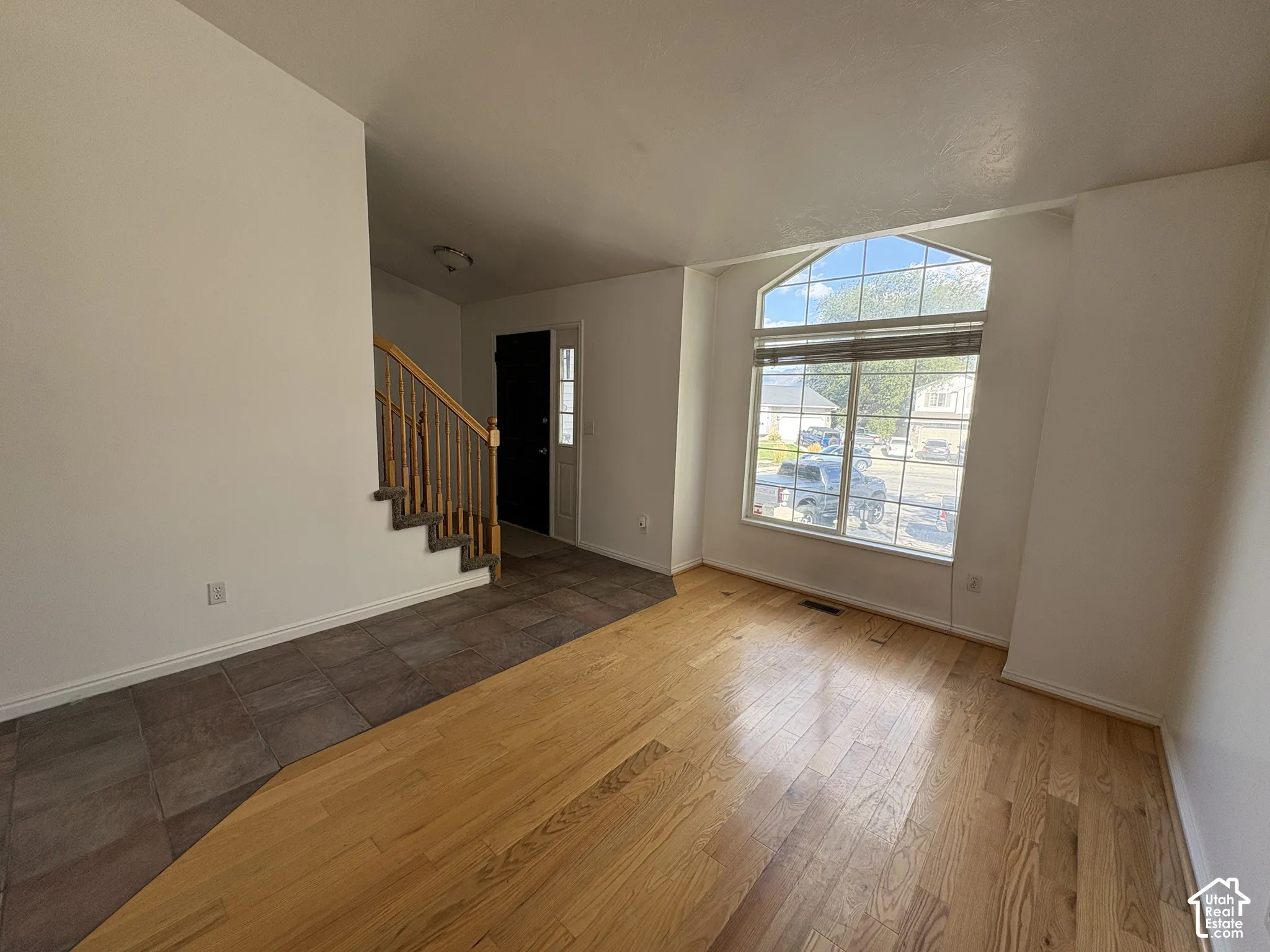 Hardwood flooring and tile flooring, arched window, staircase with wood railing,