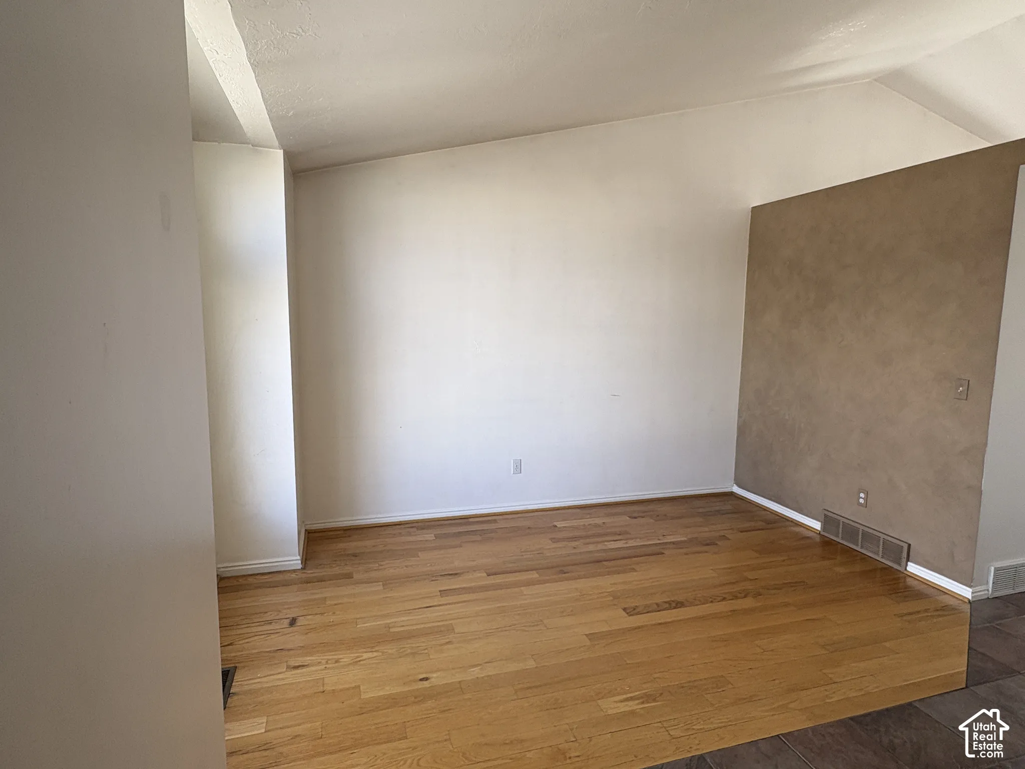 Front room off main entry with wood floors, vaulted ceiling, and textured accent wall