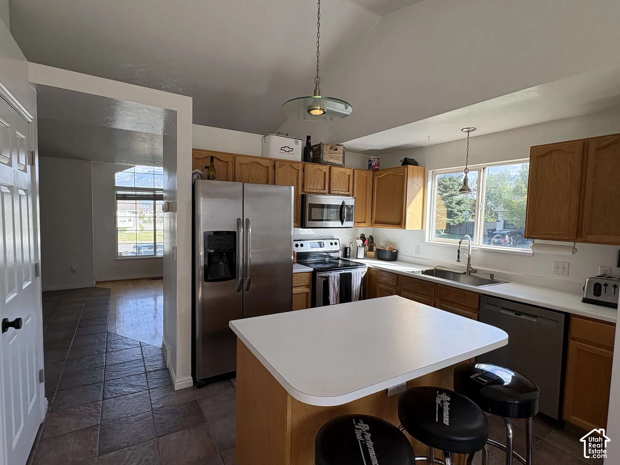 Kitchen with wood cabinetry, stainless steel appliances, white countertops, a central island, and tile flooring