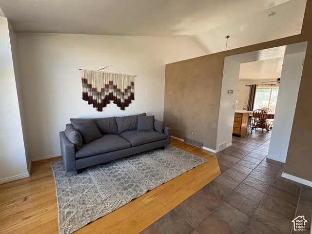 Vaulted ceiling, wood-finish flooring, tiled flooring, textured accent wall, recessed lighting