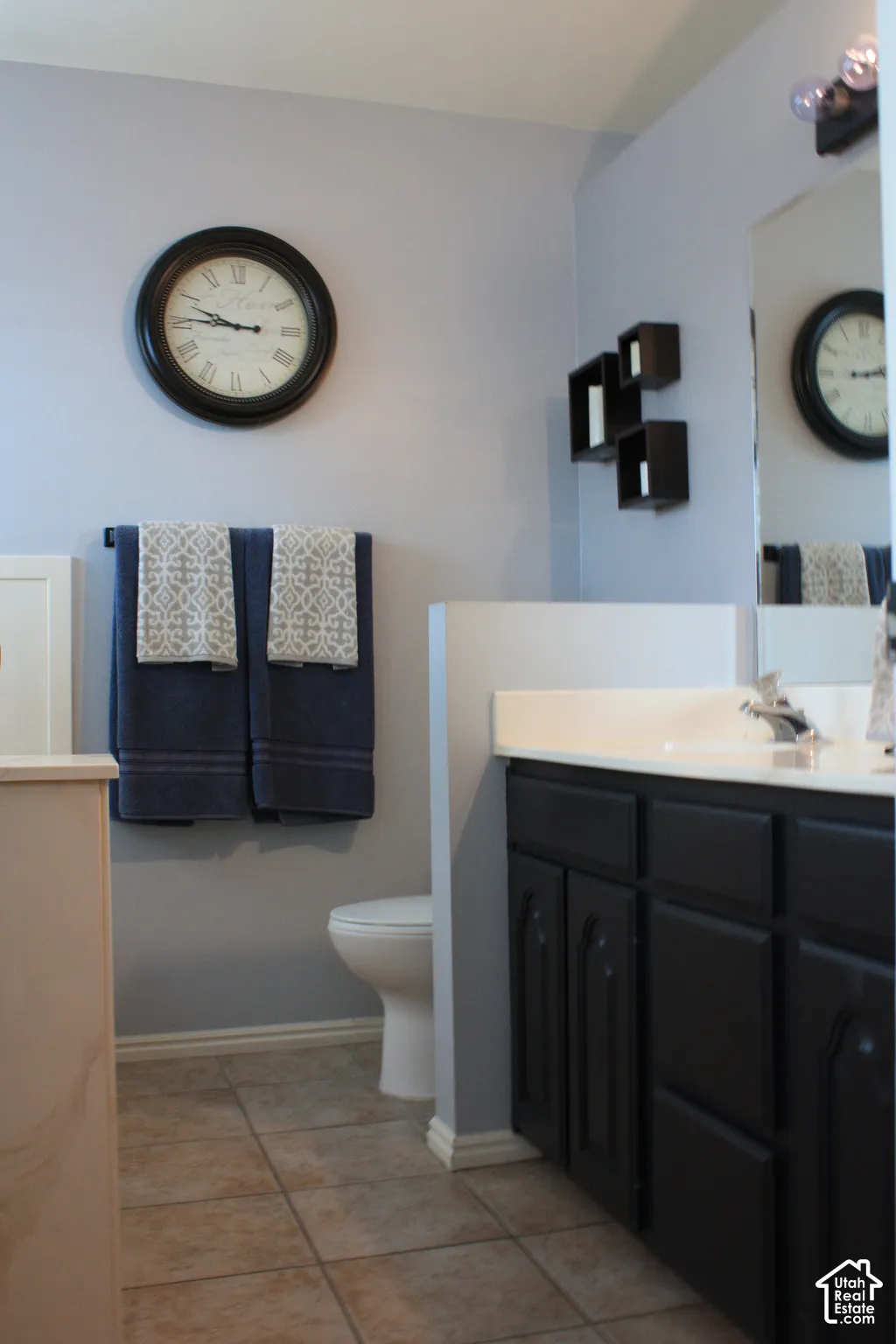 Bathroom featuring tile flooring, a dark cabinet vanity with a light-toned countertop, and a white toilet
