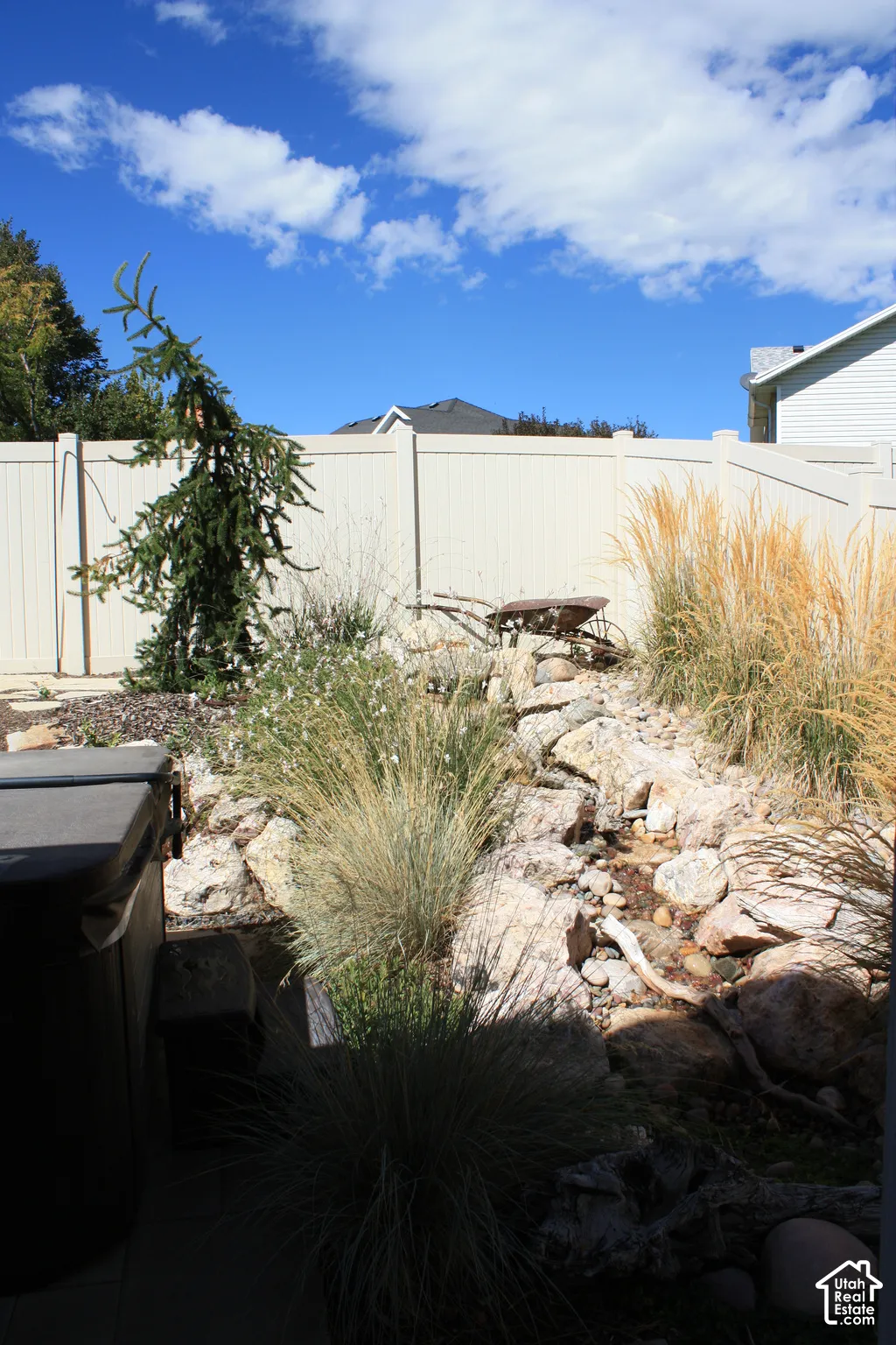 Expansive backyard featuring a rock garden, mature ornamental grasses, and a privacy fence