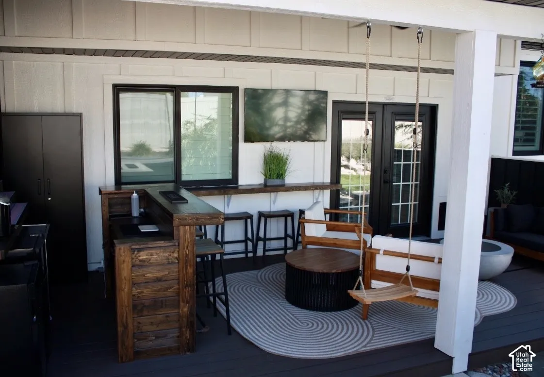 Outdoor living space featuring a built-in wood-finish bar, dedicated bar seating, and double French doors