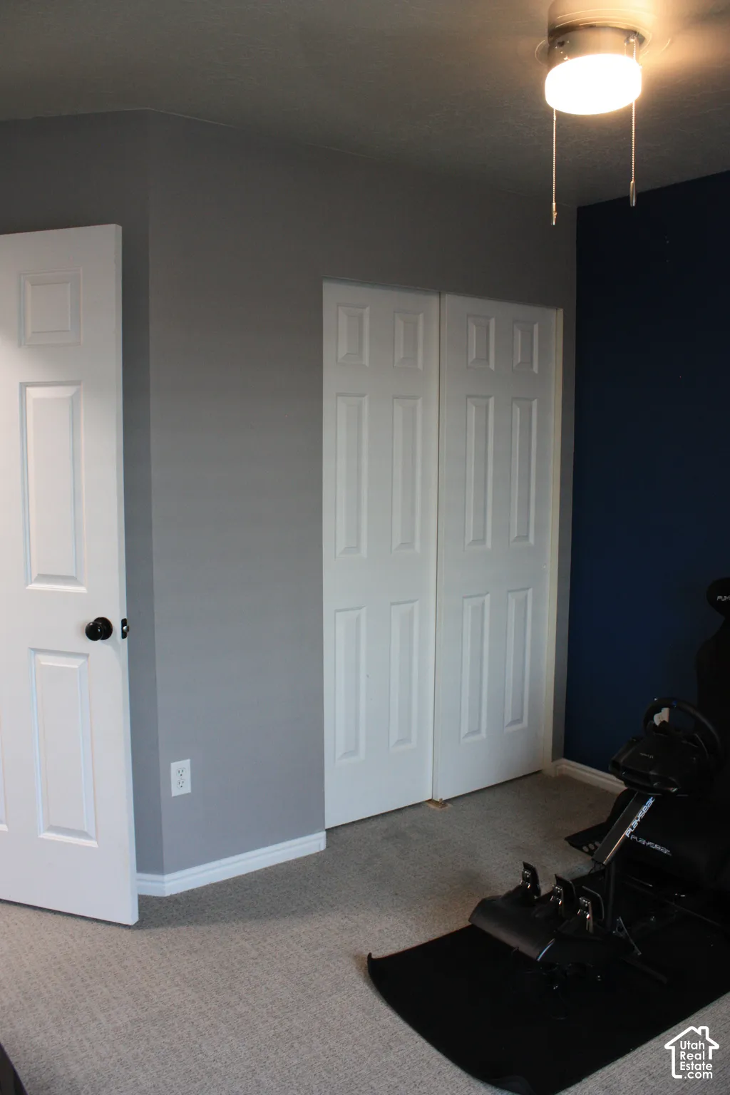 Light-colored carpeting, white paneled door, bi-fold paneled closet doors, and ceiling-mounted light fixture
