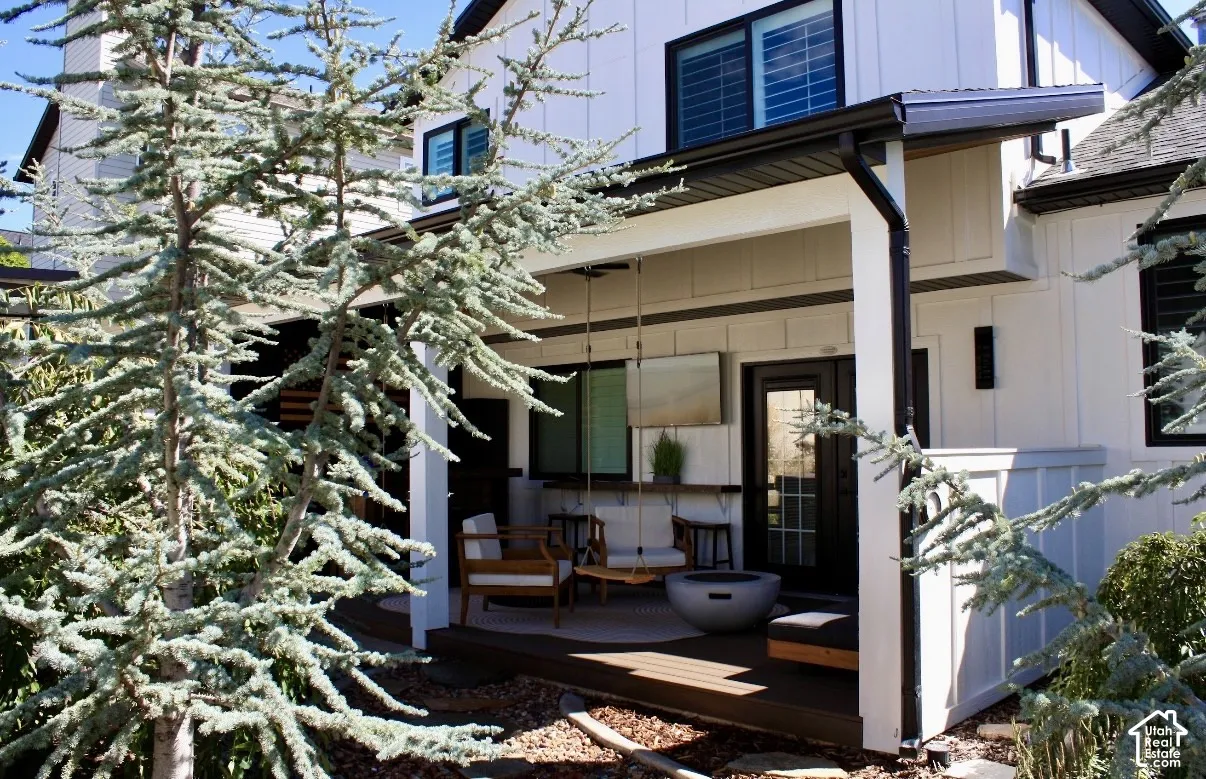 Covered patio featuring a dark wood-finish deck and white structural columns
