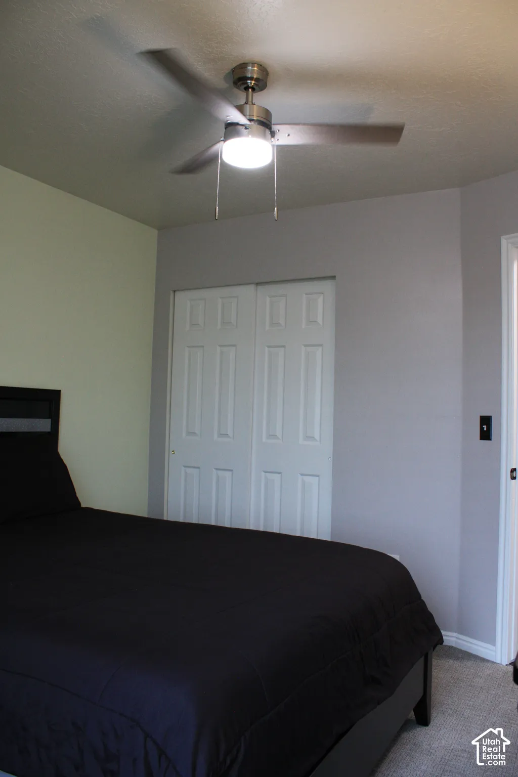 Ceiling fan with integrated lighting, bi-fold closet doors, and carpeted flooring
