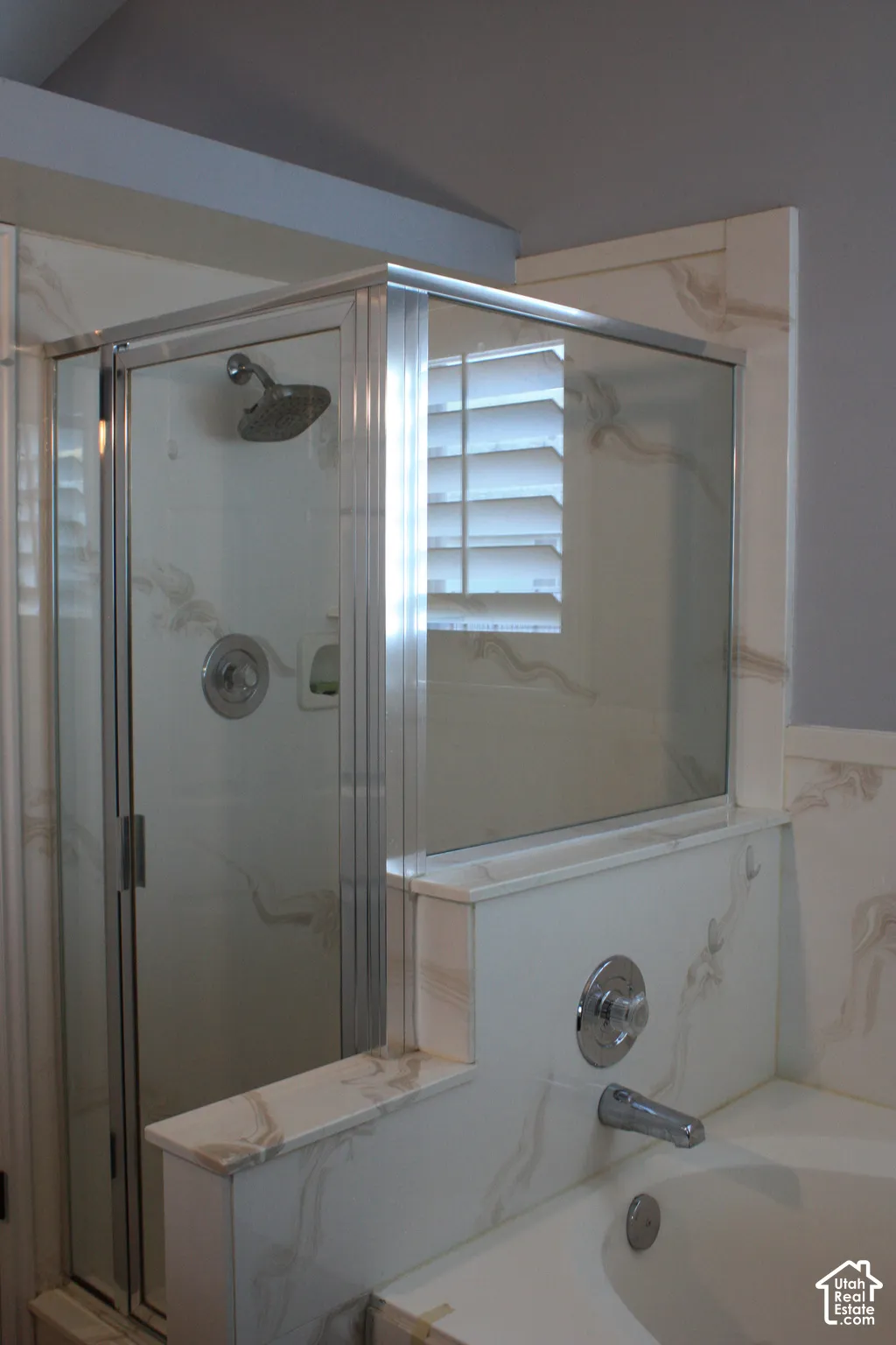 Shower enclosure with clear glass panels, chrome shower fixtures, built-in bathtub, and coordinating wall-mounted bath faucet