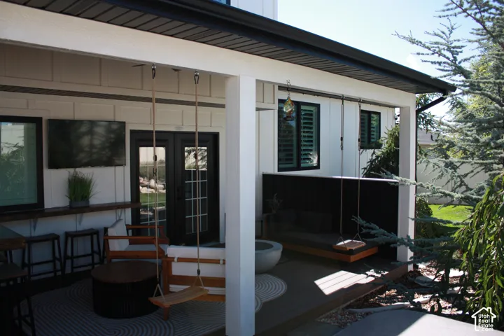 Covered patio featuring a wood-finish bar, built-in outdoor seating, and black french doors