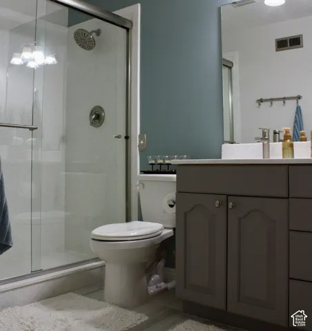 Glass-enclosed shower with a rainfall showerhead, single vanity with a white countertop, and a built-in cabinet