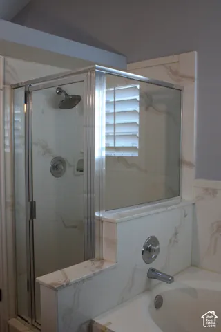 Shower enclosure with clear glass panels, chrome shower fixtures, built-in bathtub, and coordinating wall-mounted bath faucet