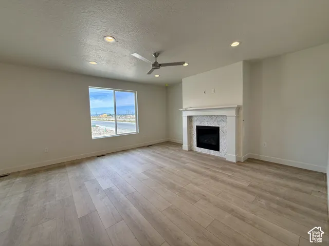 Spacious room featuring wood-finish flooring, a contemporary ceiling fan, and recessed lighting