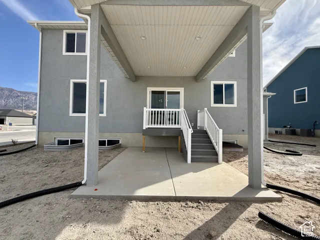 Covered patio with recessed lighting, concrete slab, and staircase with white railings