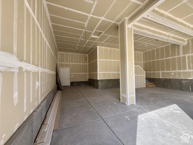 Concrete flooring with exposed drywall and a white interior door