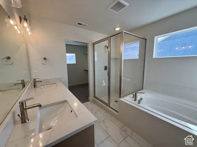 Spa-inspired primary bathroom featuring dual vanities with vessel sinks and polished nickel fixtures, quartz countertops, frameless glass shower enclosure, soaking tub, tile flooring, and abundant natural light from transom windows