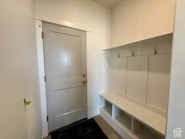 Built-in mudroom bench with cubby storage, upper shelf, board and batten wall detailing, and bronze-finish coat hooks