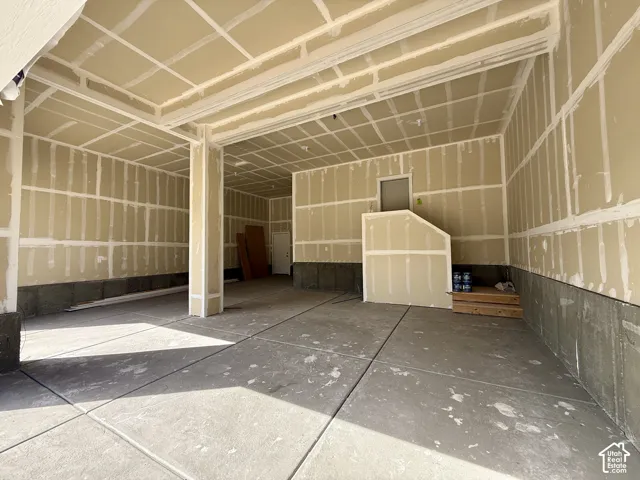 Concrete flooring in a spacious garage with drywall-ready walls and ceiling
