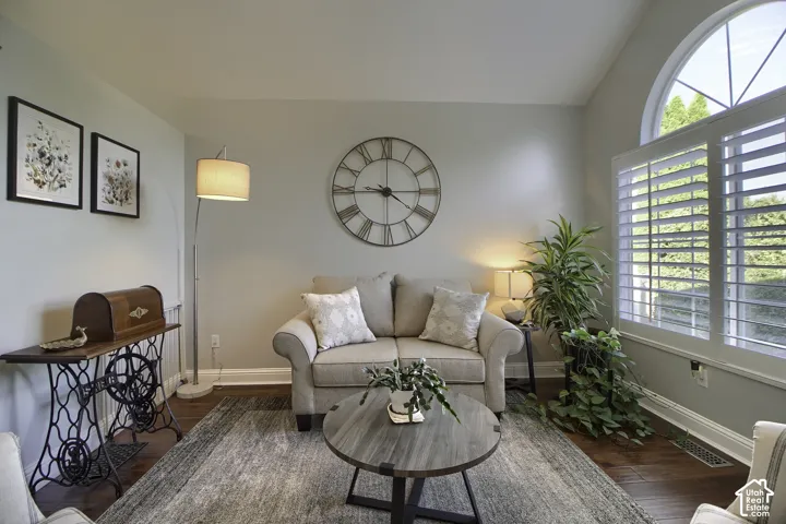 Hardwood flooring, arched window with white plantation shutters, and a classic wall clock