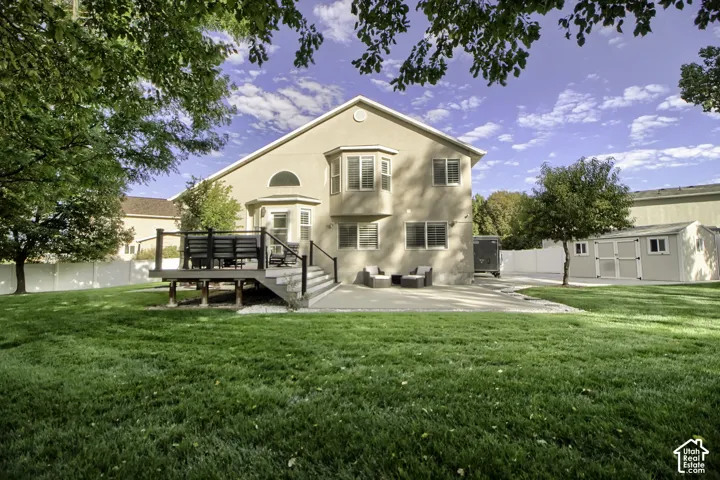 Expansive lawn with a raised outdoor deck and a concrete patio