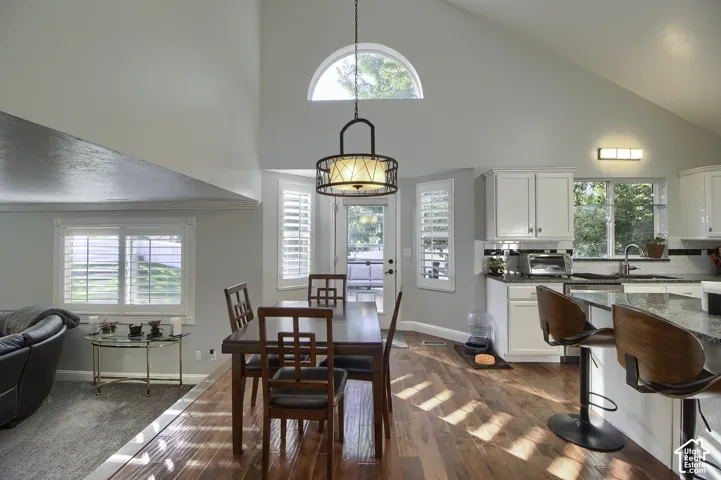 Vaulted ceiling featuring an arched window, wood-finish flooring, white cabinetry, and a kitchen island with stone countertops