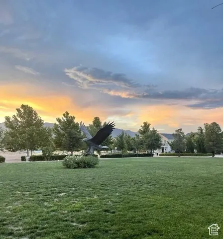 Expansive green lawn, mature trees, mountain backdrop, and a distant property